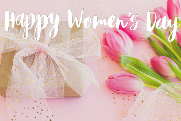 Happy womens day text on pink tulips and gift box  on pink background. Stylish greeting card. International Women's Day. 8 march. Handwritten lettering - Photo, Image