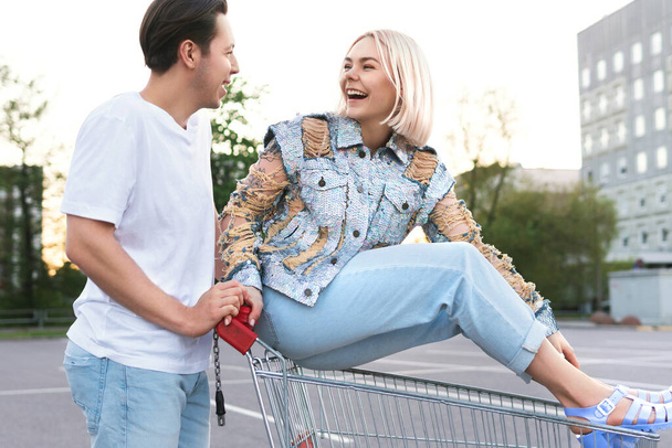 Happy young couple with a shopping trolley on supermarket parking - Foto, immagini