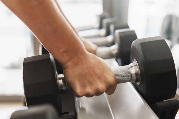 Closeup of female hands and dumbbells on the rack in gym - Foto, afbeelding
