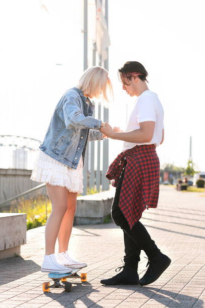 Stylish teenage couple riding longboard during their date in a city - Photo, image