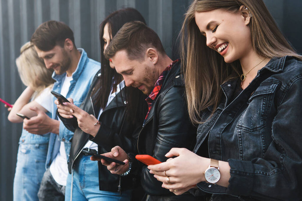 Group of young and stylish friends using smartphones for messaging instead of real communication - Foto, Imagen