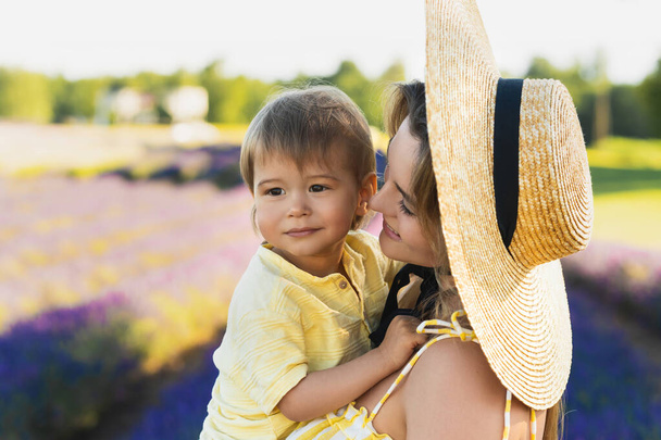 Beautiful young woman and her cute little son in the lavender field - Foto, imagen