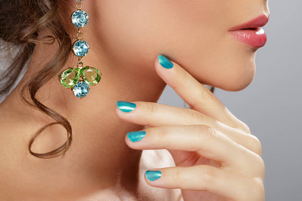Woman wearing beautiful and expensive earrings with colorful gems - Photo, image