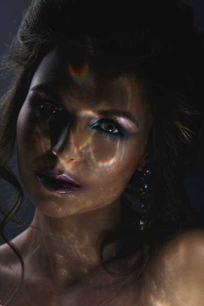 Creative portrait of beautiful woman in darkness with a light reflection on her face - Foto, immagini