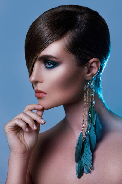 Портрет сексуальної моделі в стильному зображенні з гладким волоссям, що покриває одне око і сережки з пір'ям
 - Фото, зображення