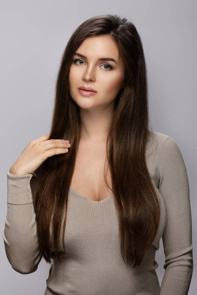 Portrait of young pretty woman with a beautiful long hair on gray background - Fotó, kép