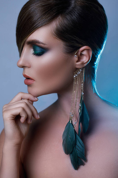 Portrait of sexy model in stylish image with sleek hair covering one eye and feather earring - Foto, Imagen