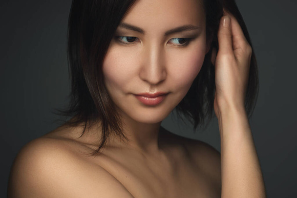 Portrait of young and beautiful asian woman on gray background - Foto, Imagen