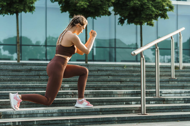 Young athletic woman doing lunges during her street workout - Foto, Bild