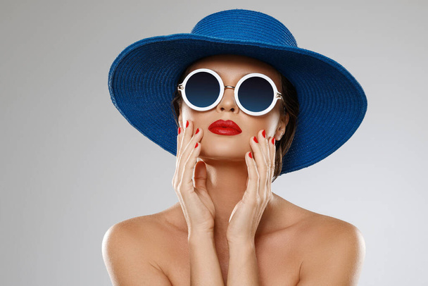 Mladá a krásná žena s modrým kloboukem a slunečními brýlemi je připravena na dovolenou - Fotografie, Obrázek