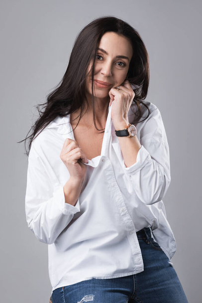 Portrait of beautiful middle aged fashion model wearing white shirt and jeans in a photo studio - Foto, immagini