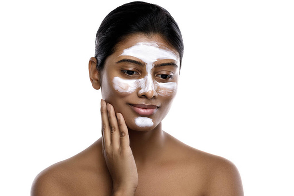 Giovane donna indiana con una maschera detergente applicata sul viso su sfondo bianco. - Foto, immagini