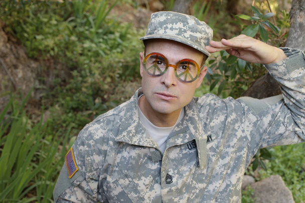 portrait en gros plan d'un beau jeune soldat avec des lunettes symbole de paix - Photo, image