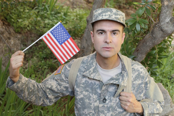portrait en gros plan d'un beau jeune soldat en uniforme avec drapeau américain - Photo, image