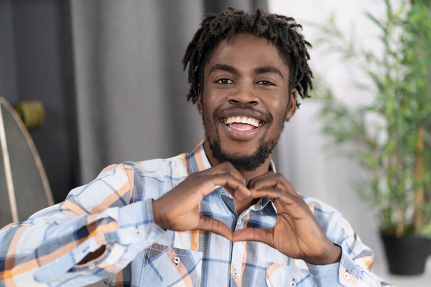 Charming african man in plaid shirt send love sign gesturing it with hands. African american male model makes love figure by his hands.High quality photo - 写真・画像