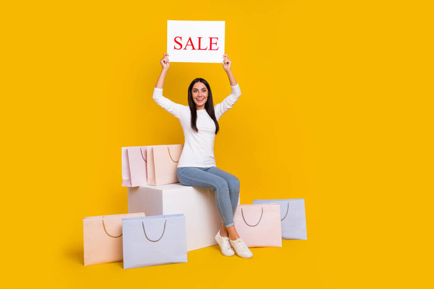 Full size photo of young excited woman hold paper poster information discount shopping isolated over yellow color background - Foto, imagen
