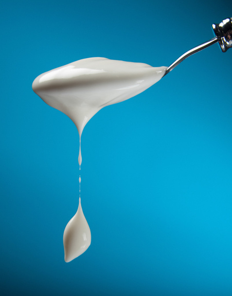 Spoon with yogurt on a blue background - Photo, Image