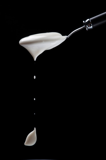 Spoon with yogurt on a black background - Фото, зображення