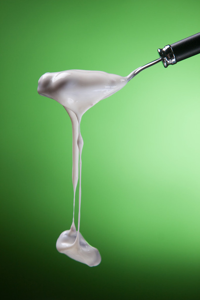 Spoon with yogurt on a green background - Photo, Image