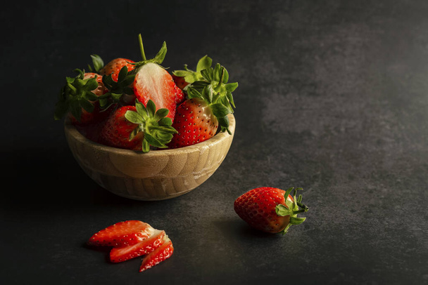 fresh ripe strawberries in a bowl on a black background. - Foto, Imagen