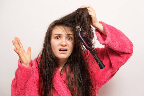 Una mujer con el pelo enredado largo húmedo trata de peinar - Foto, imagen