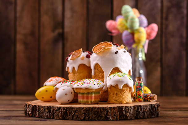 Праздничные торты с белой глазурью, орехами и изюмом на праздничном столе. Подготовка к Пасхе - Фото, изображение