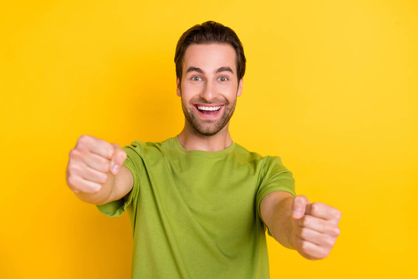 Photo of impressed beard millennial guy drive wear green t-shirt isolated on yellow color background - 写真・画像