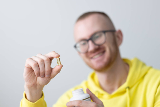 Un homme souriant tenant des vitamines dans sa main. Gros plan. Soins de santé et médecine. - Photo, image