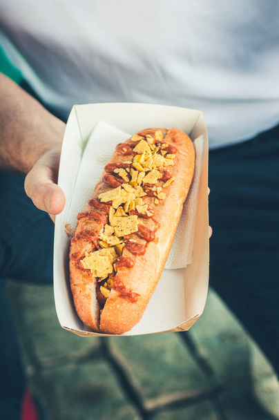 Freshly prepared hotdogs in a paper box in a hand. Food delivery concept. - Foto, Imagen