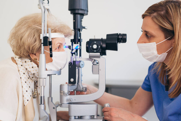 the older woman has an ophthalmologic examination. corona virus concept - Fotografie, Obrázek
