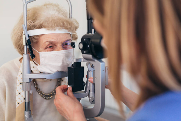 the older woman has an ophthalmologic examination. corona virus concept - Foto, afbeelding