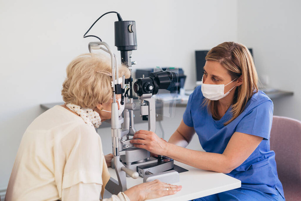 the older woman has an ophthalmologic examination. corona virus concept - Foto, afbeelding