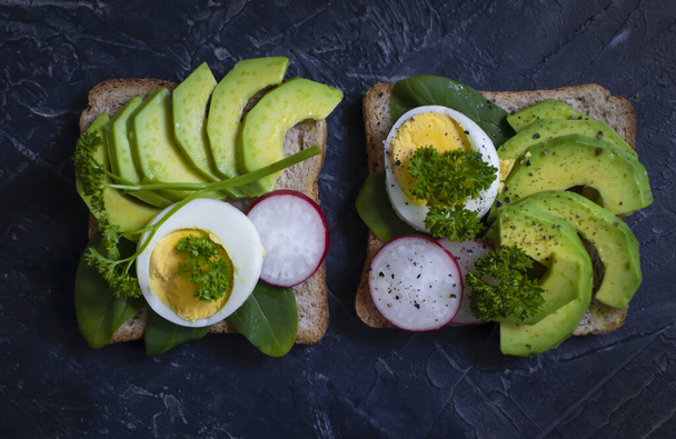 Yumurtalı sandviç, avokado, eski arkaplanda turp yeşili. - Fotoğraf, Görsel