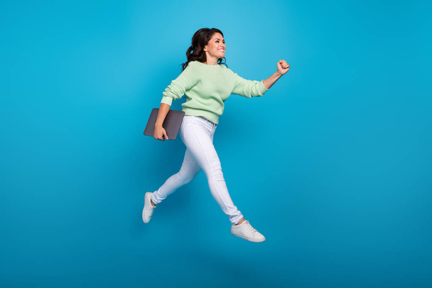 Full length body size view of attractive cheerful woman jumping holding laptop going isolated over bright blue color background - Photo, image