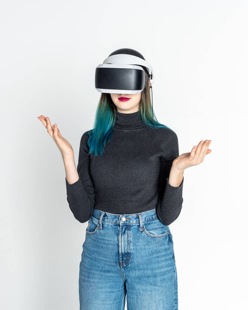Teen girl using vr headset is in virtual reality cyberspace vhite background, vertical frame. The concept of the metaverse - Fotoğraf, Görsel