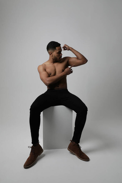 Studio photo of strong athletic black man shows naked muscular body. Vertical. - Zdjęcie, obraz