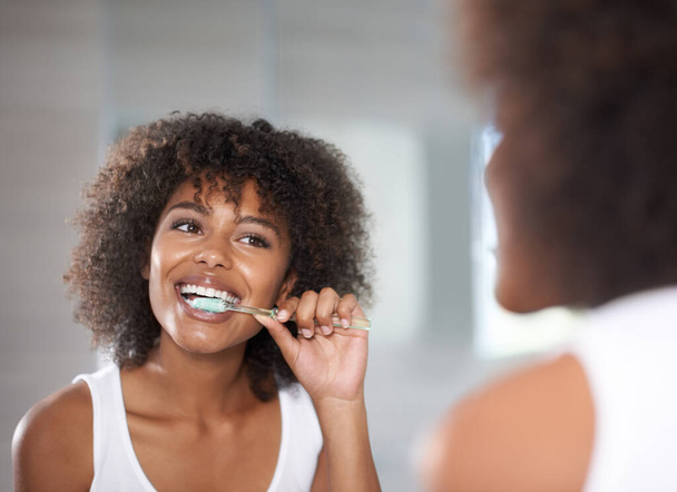 Keeping her smile. Shot of a a young woman brushing her teeth. - Photo, image