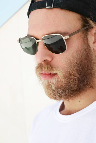 Close-up portrait of bearded man posing outdoor wears sunglasses. Vertical. - 写真・画像