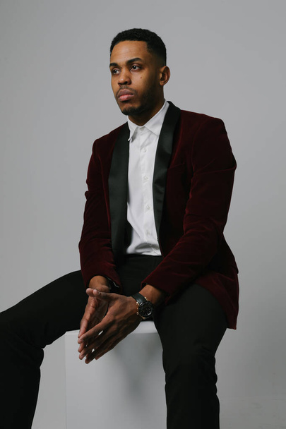 Young and handsome black man wearing brandy suit posing over grey background. - Foto, immagini