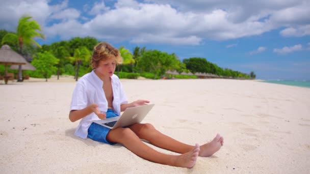 Jongen bij online les bij leraar. Kind gebruiken laptop tegen de achtergrond van het turquoise water. Jonge jongen woont een online les bij tijdens de lockdown - Video