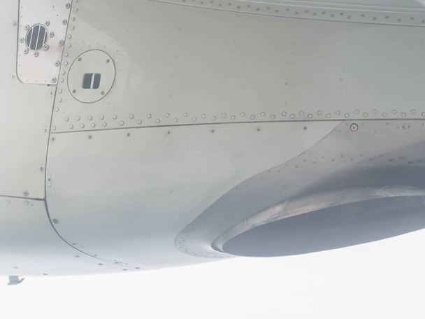 Θραύσμα μιας μίνι πτέρυγας αεροπλάνου με ραφές και μεταλλικές βίδες. Κοντινές φωτογραφίες. Θέα από το παράθυρο του αεροπλάνου - Φωτογραφία, εικόνα