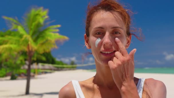 Een vrouw passeert zonnecrème op gezicht op een zonnige dag - Video