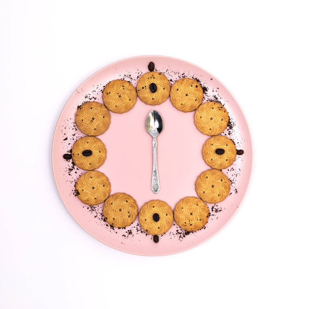 Some cookies served on a pink plate with coffee sprinkles with a teaspoon in the center on a white background, top view, flat lay, copyspase, square - Photo, image