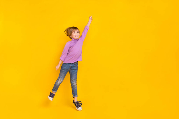 Full size photo of good mood cute little boy flying holding invisible parasol isolated on yellow color background - Фото, зображення
