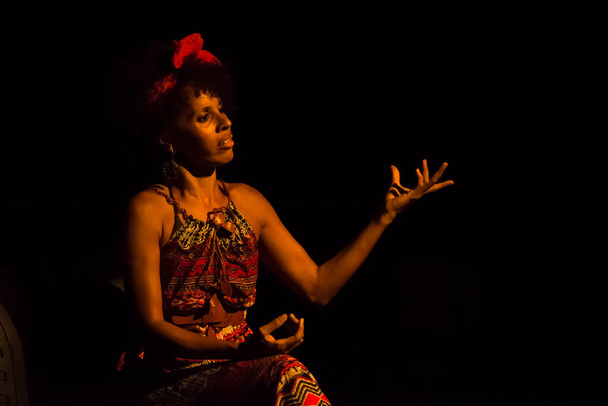 Actrice op een stoel in het theater die een personage speelt in een show. Zwarte achtergrond. Salvador Bahia Brazilië. - Foto, afbeelding