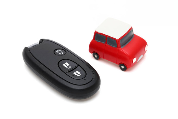 Auto zwarte sleutel afstandsbediening en klein speelgoed auto op witte achtergrond  - Foto, afbeelding