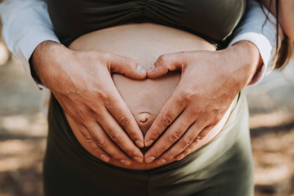 Padri mani a forma di cuore toccando madri pancia maternità incinta. Concetto di gravidanza. Genitorialità - Foto, immagini
