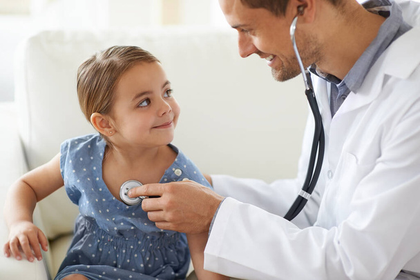 Lets have a listen. Shot of a handsome male doctor with an adorable young girl for a patient. - Foto, Bild