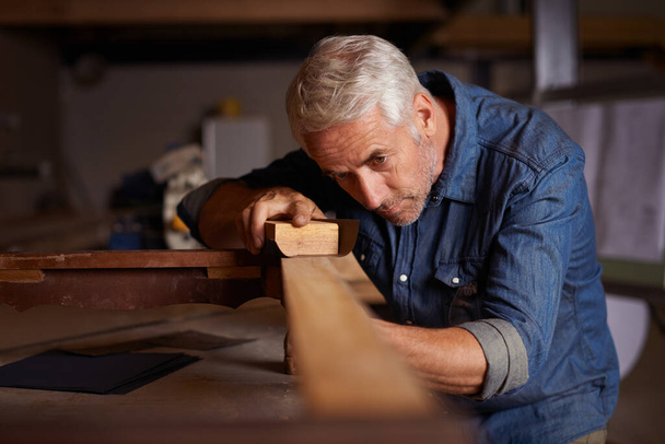 Holzarbeiten pro. Aufnahme eines gestandenen männlichen Tischlers bei der Arbeit an einem Projekt in seiner Werkstatt. - Foto, Bild