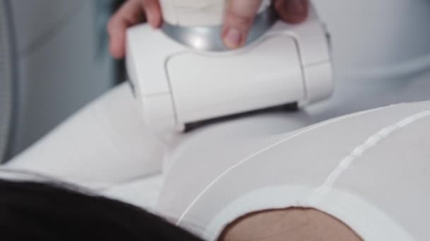 Młoda kobieta otrzymuje elektryczny masaż na ciele ubrana w specjalny biały garnitur - Materiał filmowy, wideo
